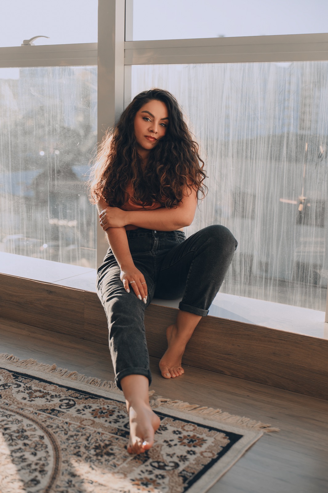 Ari Telles sentada junto a uma janela iluminada